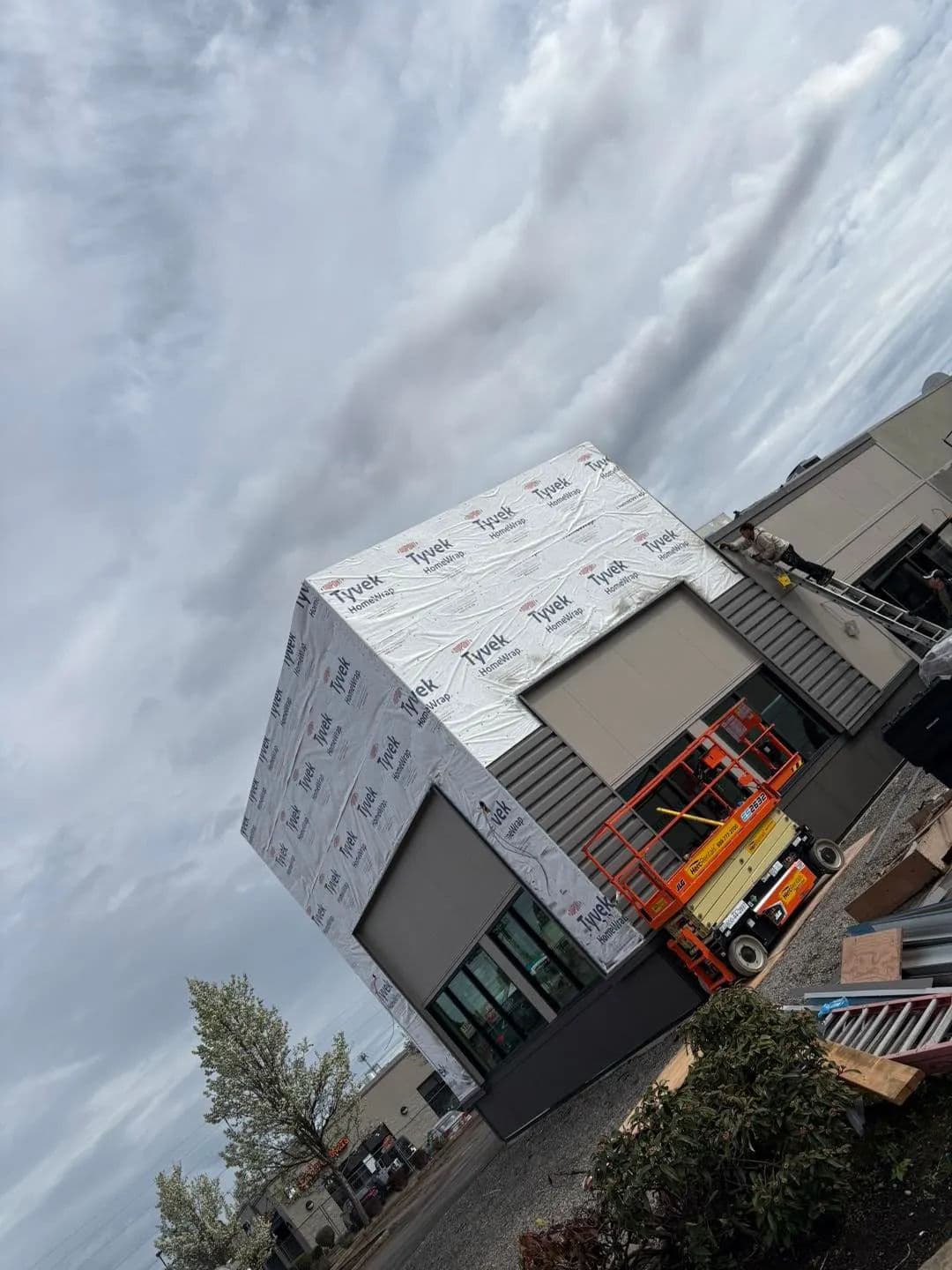 Modern building under construction with scaffolding and sky backdrop.