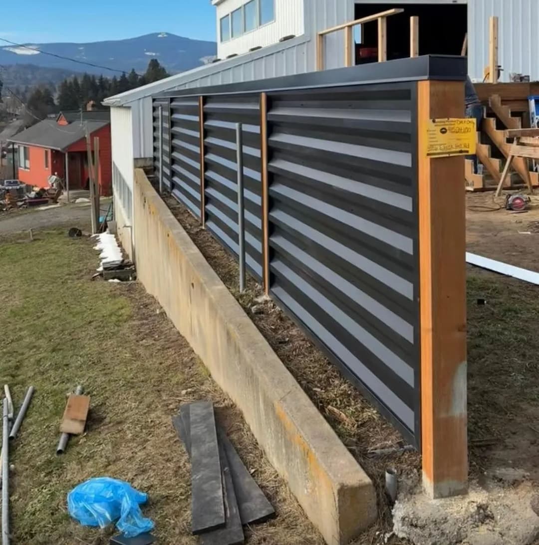 Modern corrugated metal fence with wooden posts, set in a landscaped yard.