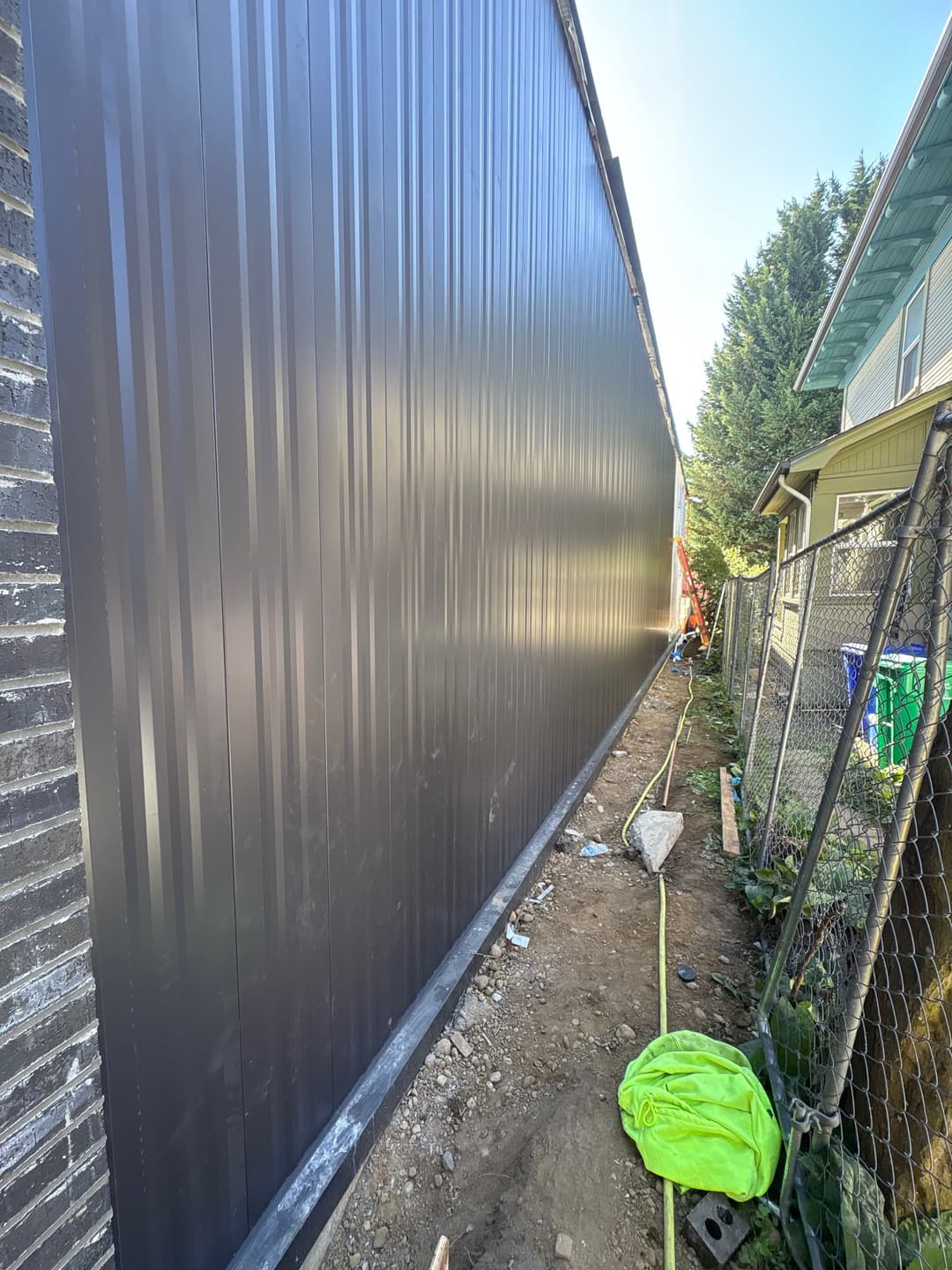 Newly installed black corrugated metal siding along a residential building's exterior.